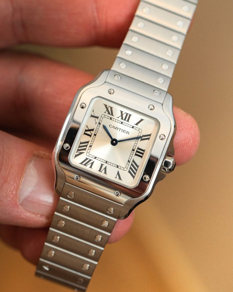 Santos de Cartier Quarz mit silbernem Zifferblatt und Edelstahlgehäuse am Edelstahlarmband in einer Hand gehalten