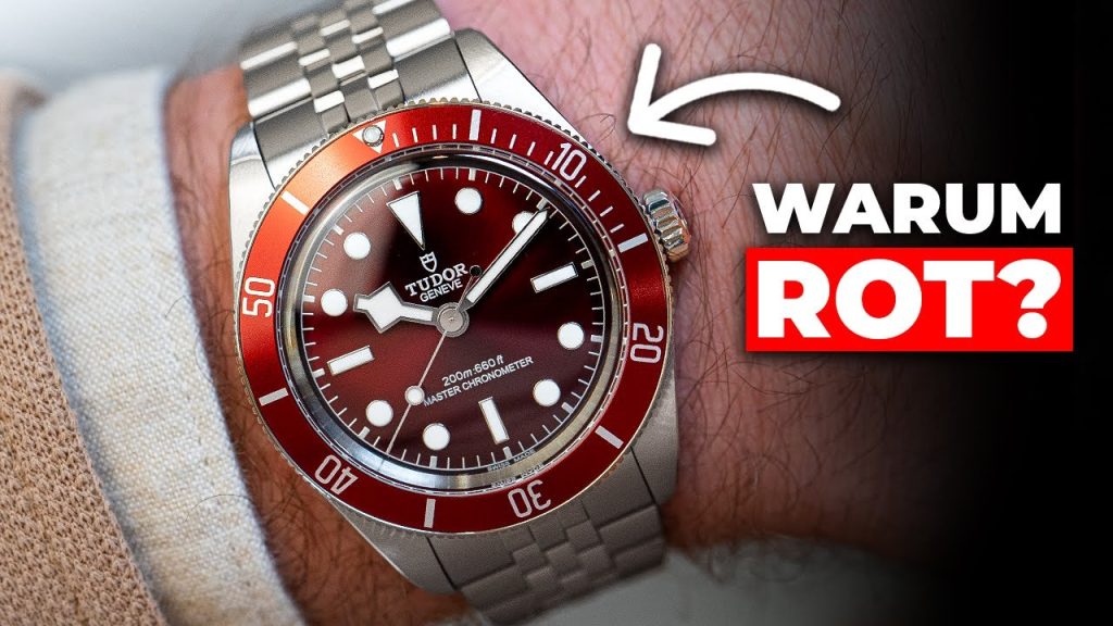 Die TUDOR Black Bay 58 mit bordeauxrotem Zifferblatt am Edelstahlarmband an einem Handgelenk mit beigem Ärmel getragen mit weißem Pfeil, der auf die Uhr zeigt und dem Schriftzug „Warum Rot“ darunter