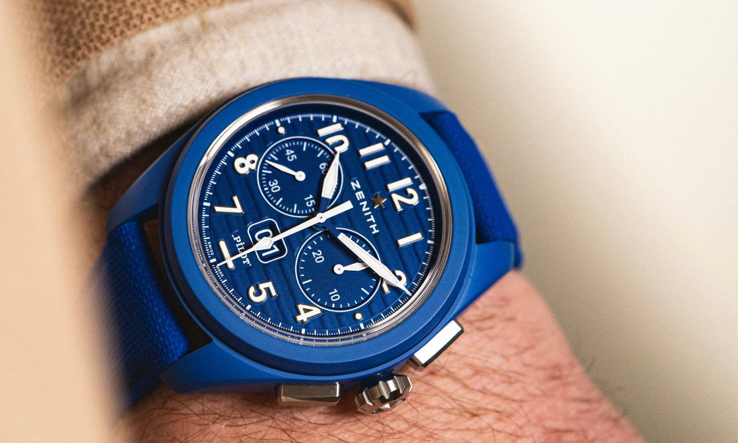 Zenith Pilot Flyback blaue Keramik mit blauem Zifferblatt am blauen Keramikarmband an einem Handgelenk mit beigem Ärmel getragen