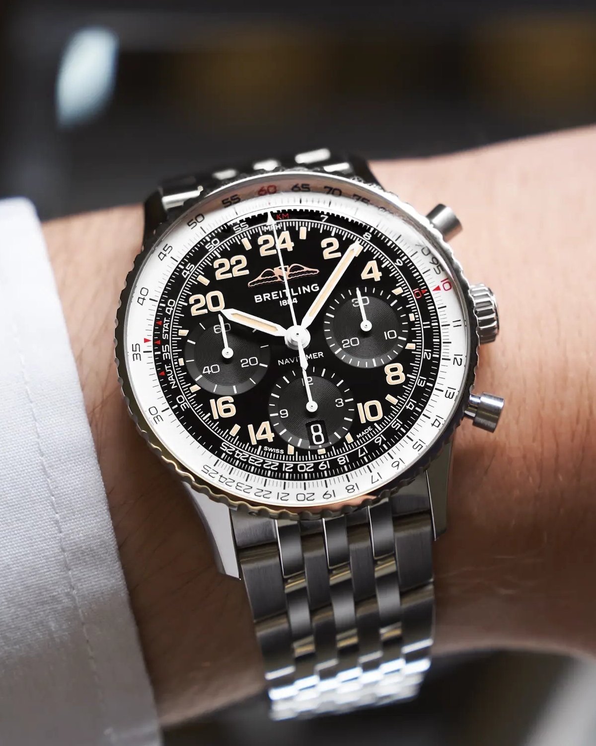 Breitling Navitimer B02 Chronograph Cosmonaute Referenz PB02301A1B1A1 mit schwarzem Zifferblatt am Edelstahlarmband an einem Handgelenk mit weißem Ärmel getragen