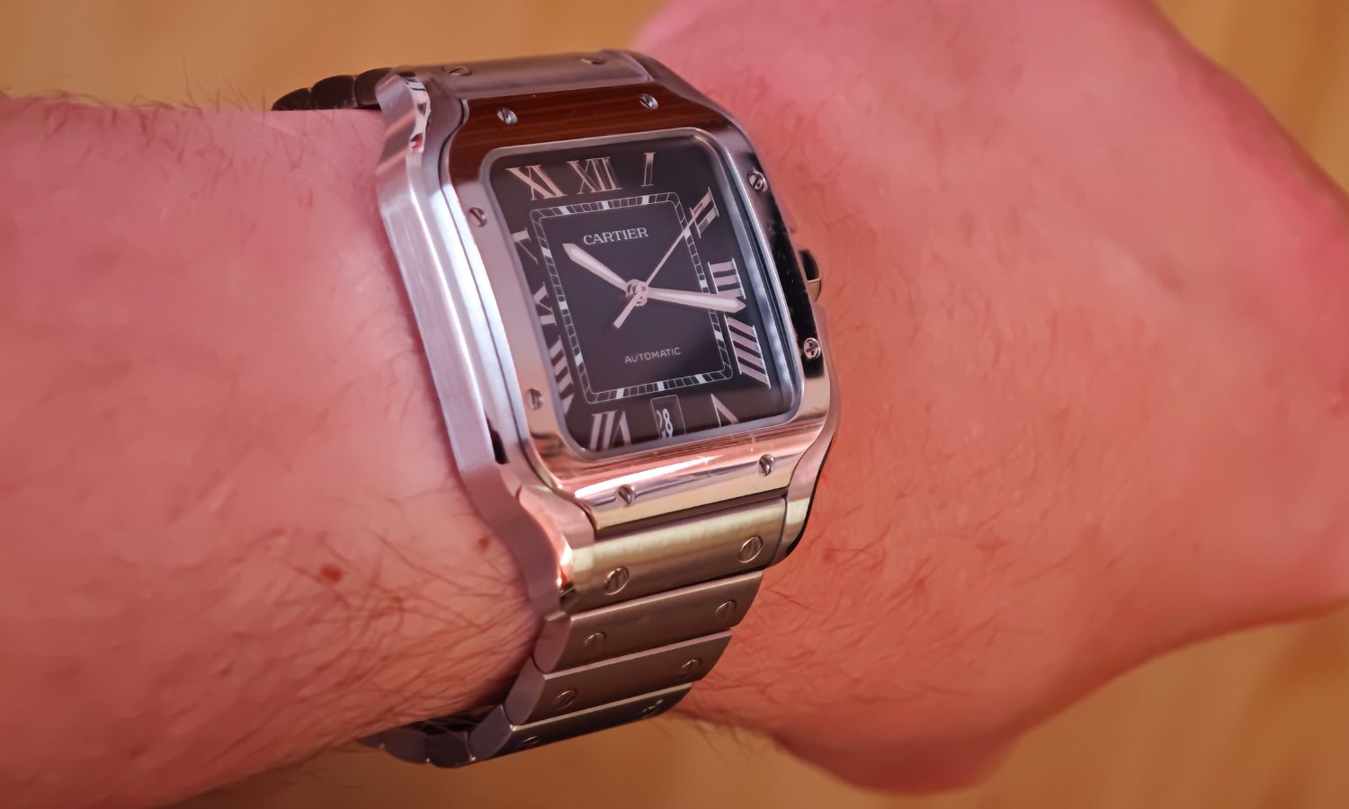 Blick auf die Cartier Santos de Cartier mit der Referenz WSSA0071 am blauen Stahlarmband auf dem Handgelenk eines Mannes.
