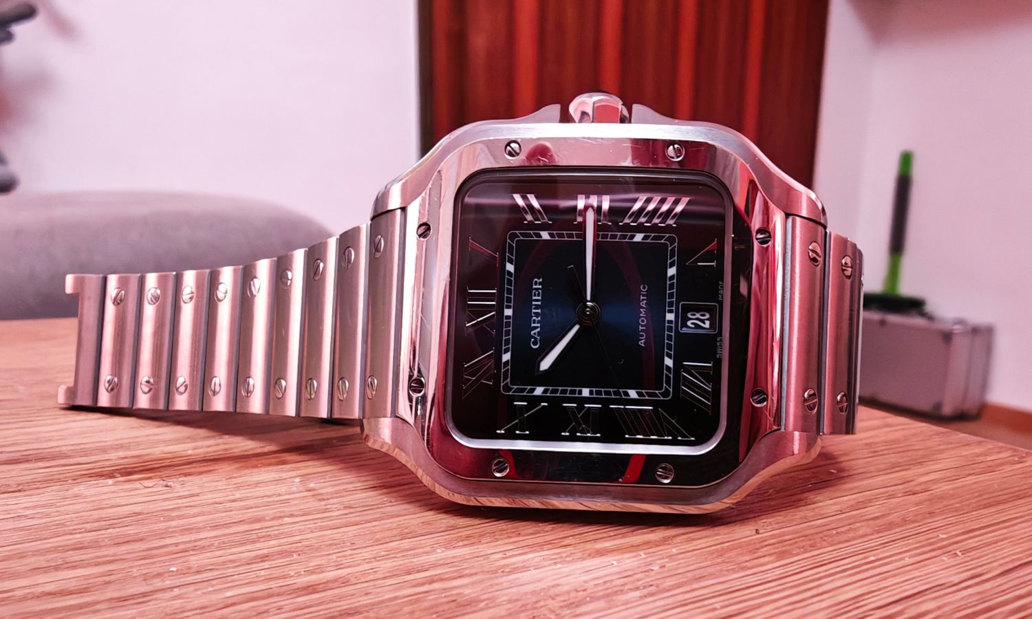 Seitlicher Blick auf die Cartier Santos de Cartier mit der Referenznummer WSSA0071, die auf einem Holztisch liegt.