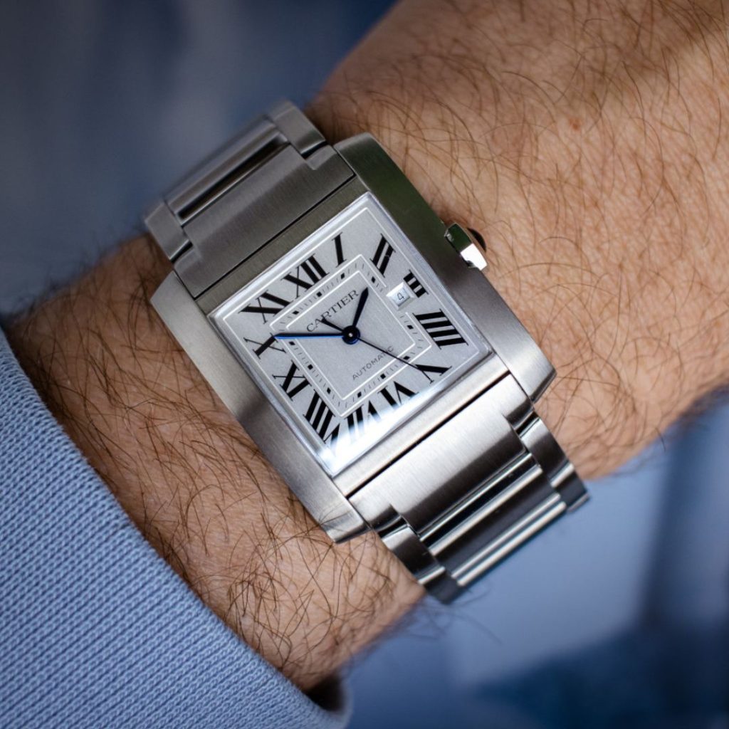 Seitlicher Blick auf die Cartier Tank Française mit der Referenz WSTA0067 auf dem Handgelenk eines Mannes.