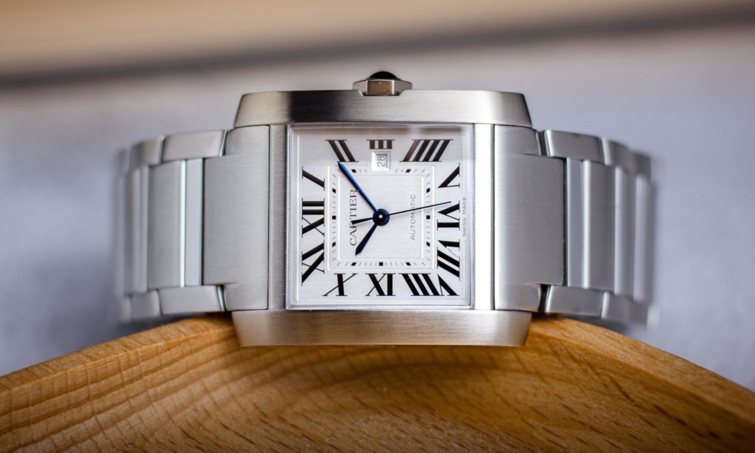 Seitlicher Blick auf die Cartier Tank Française mit der Referenz WSTA0067 auf einem Holztisch.