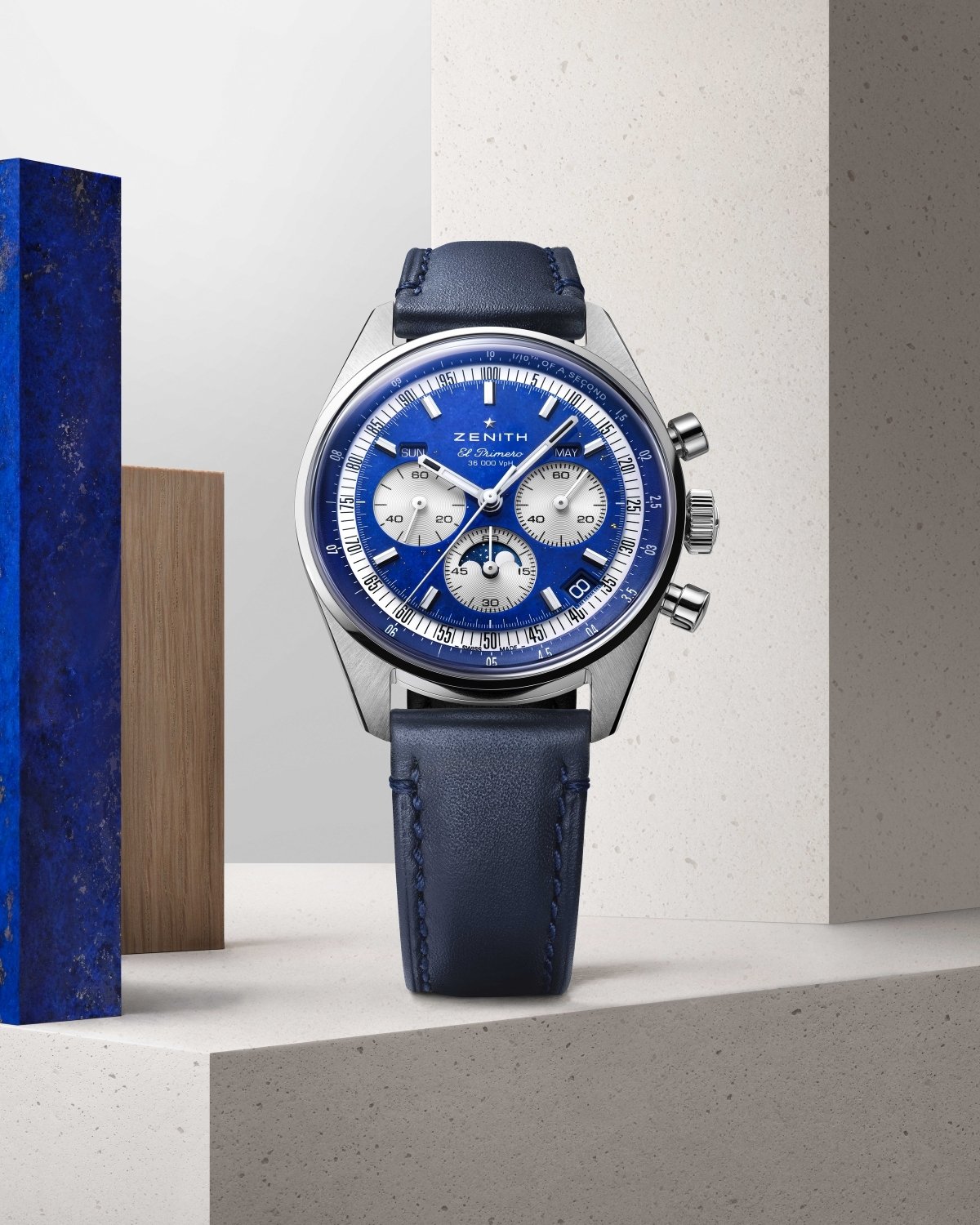 Chronomaster Original Triple Calendar Lapis mit blauem Zifferblatt am blauen Lederarmband stehend vor grauem Hintergrund
