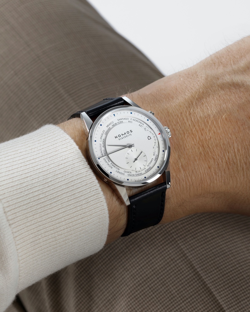 Weiße NOMOS Glashütte Zürich Weltzeit am Handgelenk eines Mannes