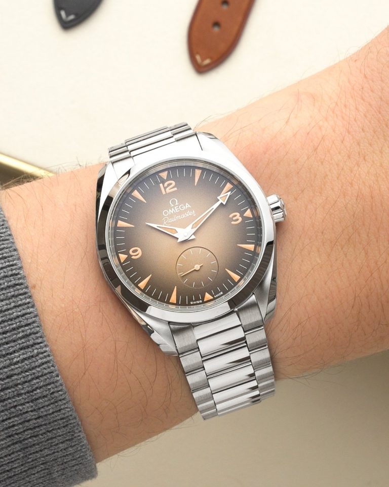 OMEGA Seamaster Railmaster Referenz: 235.10.38.20.13.001 mit beigem Zifferblatt am Edelstahlarmband an einem Handgelenk mit grauem Ärmel getragen
