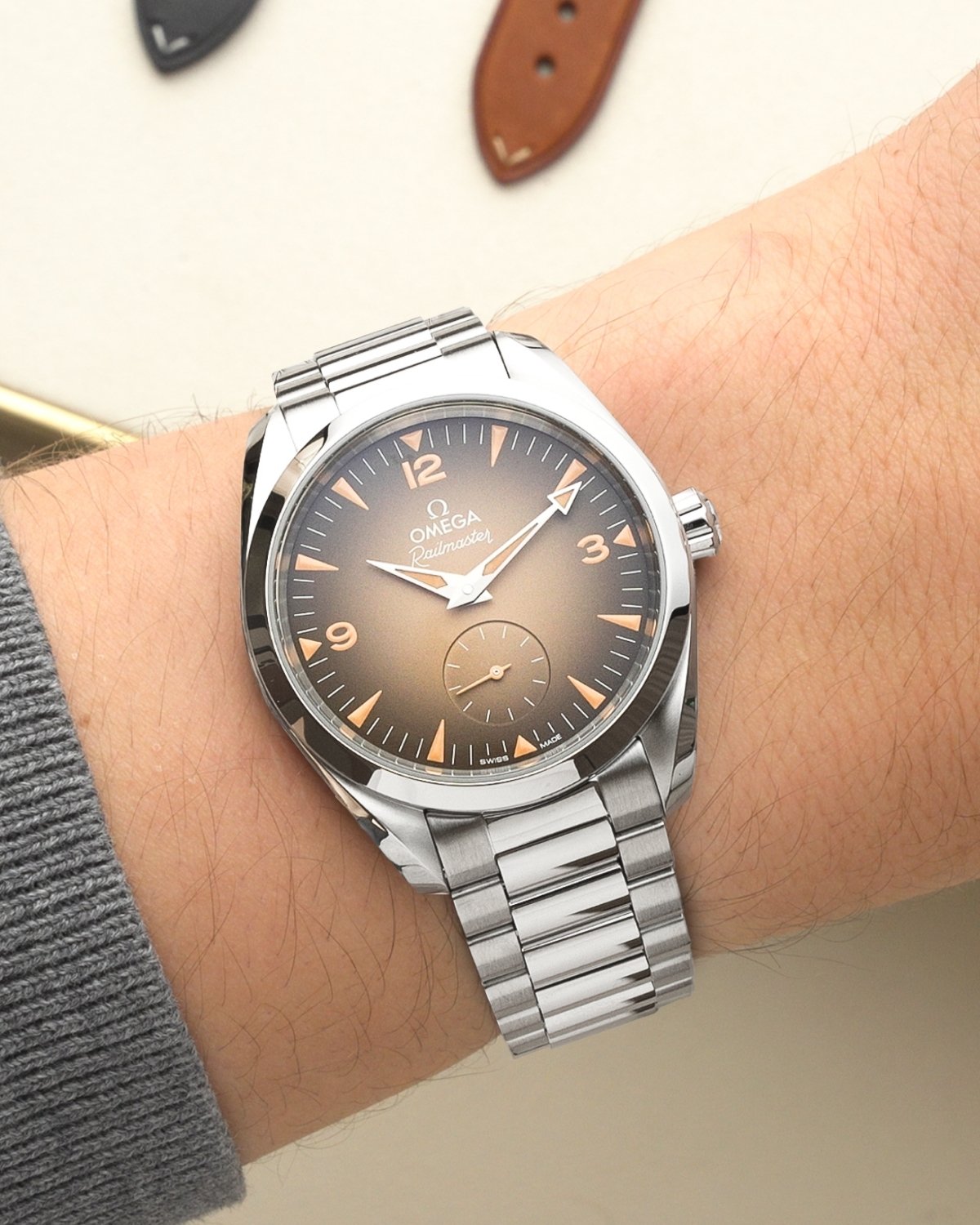 OMEGA Seamaster Railmaster Referenz: 235.10.38.20.13.001 mit beigem Zifferblatt am Edelstahlarmband an einem Handgelenk mit grauem Ärmel getragen