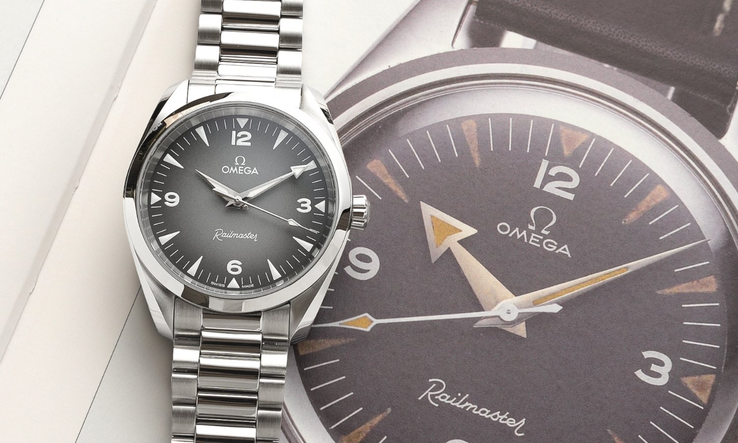 OMEGA Seamaster Railmaster Referenz: 235.10.38.20.06.001 mit grauem Zifferblatt am Edelstahlarmband auf einer OMEGA Zeitschrift mit Bild des Originalmodells der Railmaster liegend