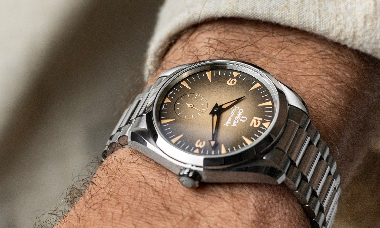 OMEGA Seamaster Railmaster Referenz: 235.10.38.20.13.001 mit beigem Zifferblatt am Edelstahlarmband an einem Handgelenk mit beigem Ärmel getragen