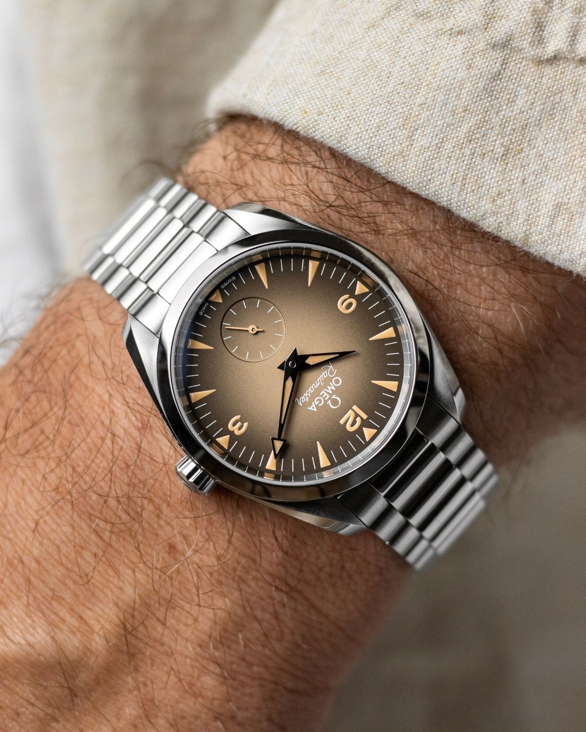 OMEGA Seamaster Railmaster Referenz: 235.10.38.20.13.001 mit beigem Zifferblatt am Edelstahlarmband an einem Handgelenk mit beigem Ärmel getragen