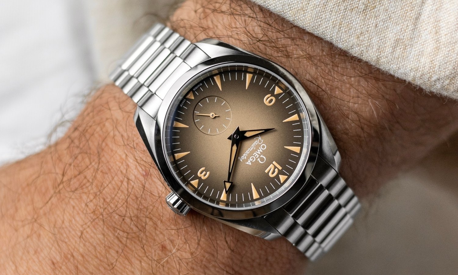OMEGA Seamaster Railmaster Referenz: 235.10.38.20.13.001 mit beigem Zifferblatt am Edelstahlarmband an einem Handgelenk mit beigem Ärmel getragen