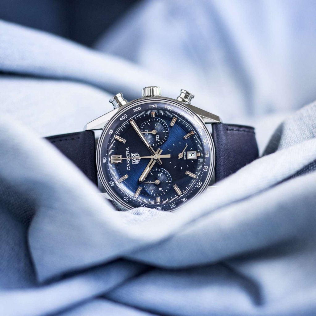 TAG Heuer Carrera Glassbox Chronograph mit blauem Zifferblatt und blauem Armband liegend auf einem hellblauen Stoff