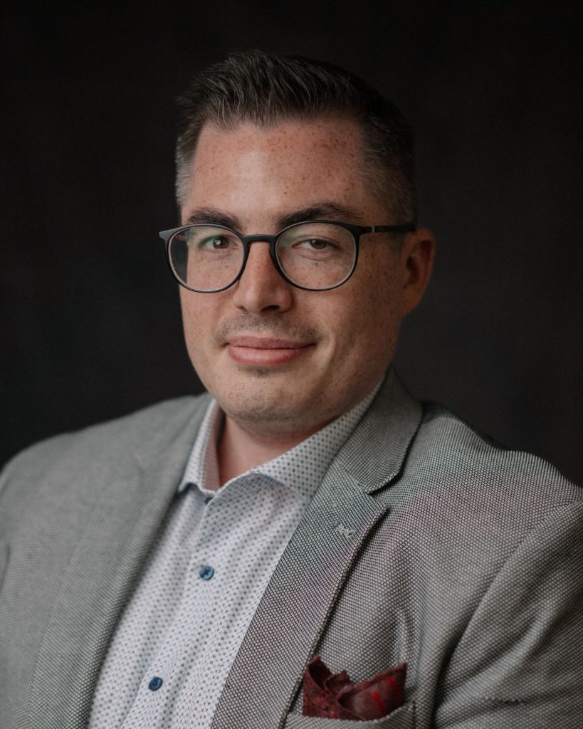 Tobias Viehöver mit heller Kleidung vor dunklem Hintergrund