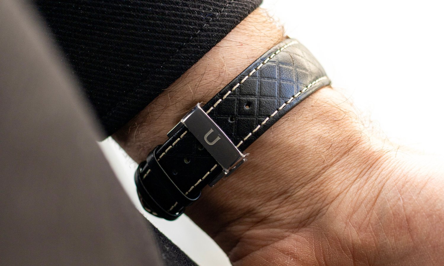 Schwarzes Lederarmband der UNION Glashütte Noramis Datum Limitierte Edition Deutschland Klassik 2025 an einem Handgelenk mit schwarzem Ärmel getragen vor hellem Hintergrund
