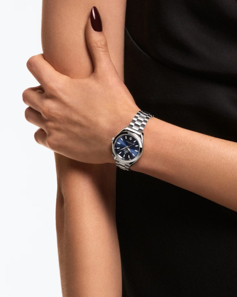 OMEGA Seamaster Aqua Terra 30 mm mit blauem Zifferblatt an dem Handgelenk einer Frau getragen vor weißem Hintergrund