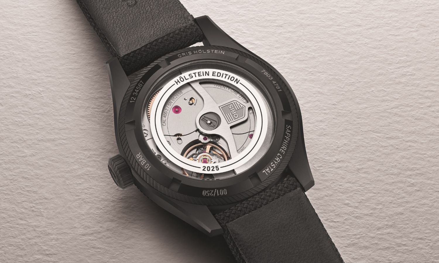 Seitlicher Blick auf das Gehäuse der ORIS Pro Pilot Hölstein Edition 2025 mit der Referenz 01 400 7803 4781-Set, die auf einem grauen Untergrund liegt.