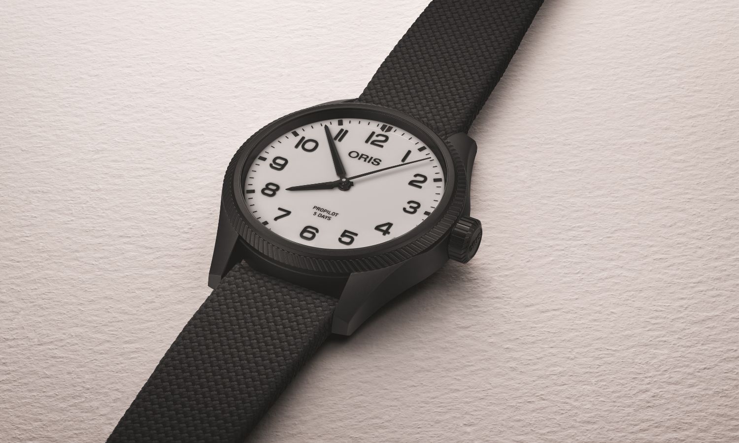 Seitlicher Blick auf die ORIS Pro Pilot Hölstein Edition 2025 mit der Referenz 01 400 7803 4781-Set, die auf einem grauen Untergrund liegt.