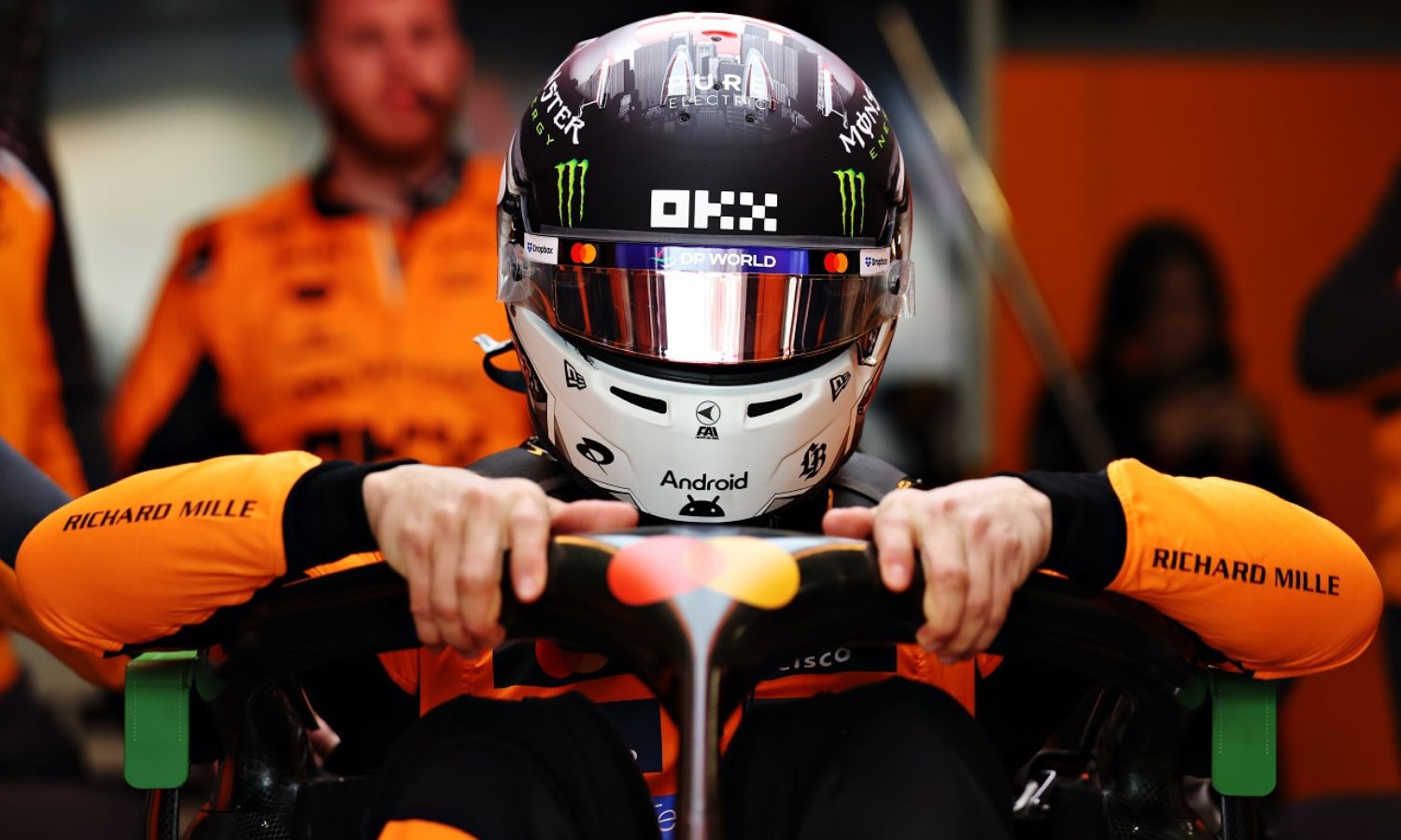 Blick von vorne auf einen Fahrer des McLaren Formel 1 Teams wie er gerade aus seinen Boliden steigt.