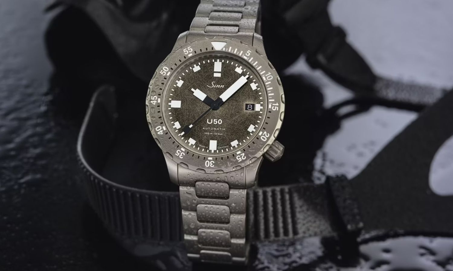 Sinn U50 DS Limited Edition am Titanarmband vor einem schwarzweißen Tauchermotiv als Hintergrund