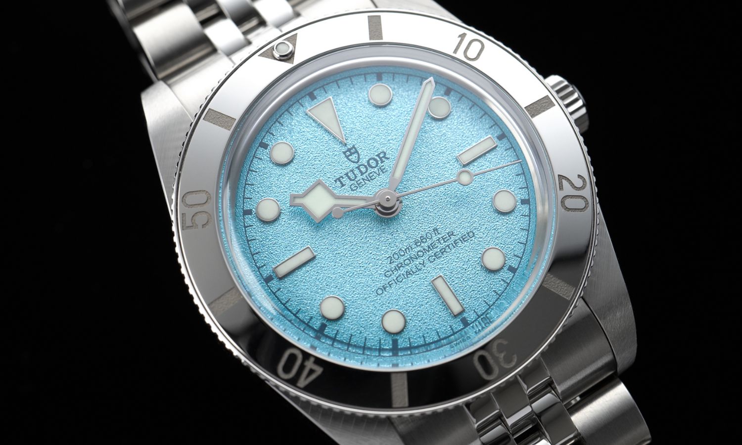 Das hellblaue Zifferblatt der TUDOR Black Bay 54 Lagoon Blue Referenz: M79000-0001 am Edelstahlarmband vor schwarzem Hintergrund