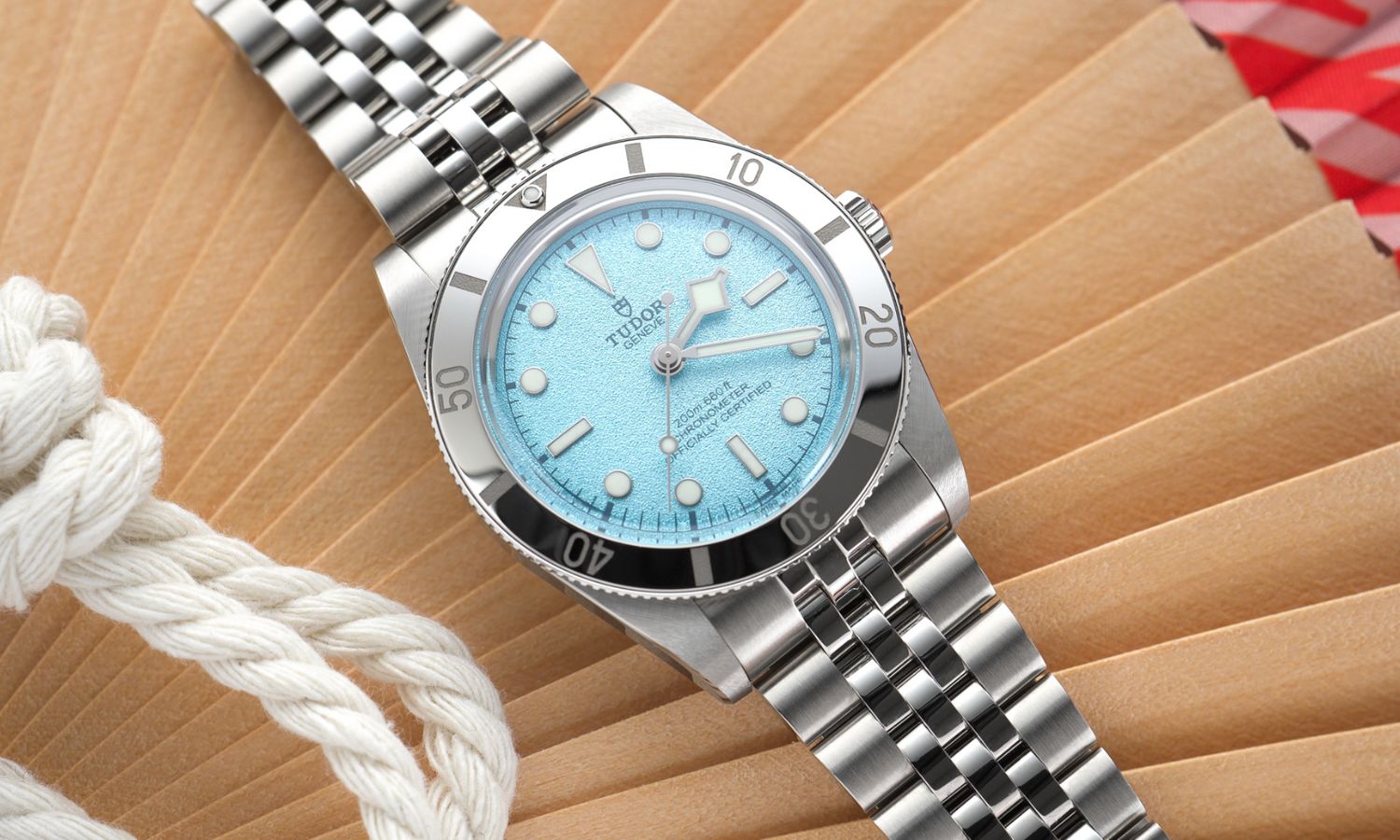 TUDOR Black Bay 54 Lagoon Blue Referenz: M79000-0001 mit hellblauem Zifferblatt am Edelstahlarmband liegend vor hölzernem Hintergrund