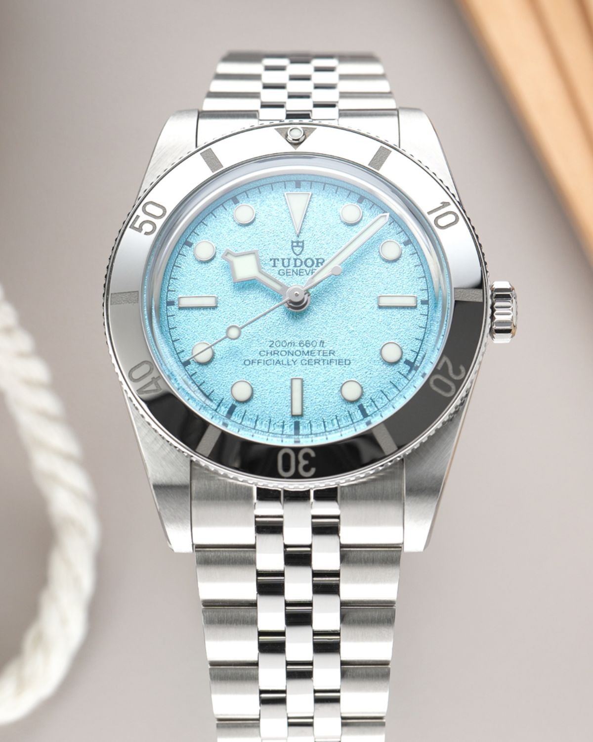 TUDOR Black Bay 54 Lagoon Blue Referenz: M79000-0001 mit hellblauem Zifferblatt am Edelstahlarmband stehend vor grauem Hintergrund