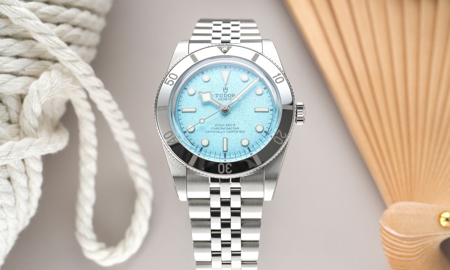 TUDOR Black Bay 54 Lagoon Blue Referenz: M79000-0001 mit hellblauem Zifferblatt am Edelstahlarmband stehend vor grauem Hintergrund