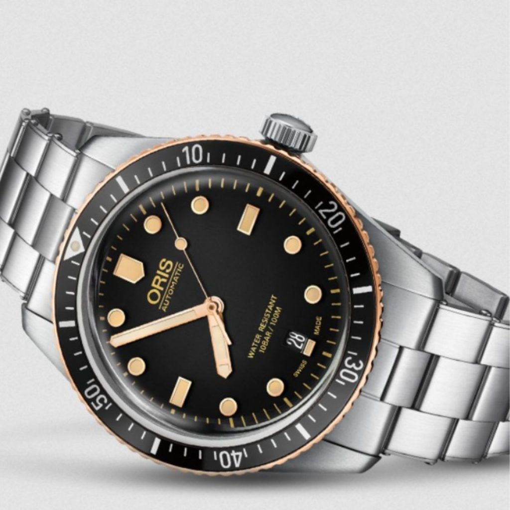 ORIS Divers Sixty Five mit schwarzem Zifferblatt und schwarzer Lünette am Edelstahlarmband liegend vor weißem Hintergrund