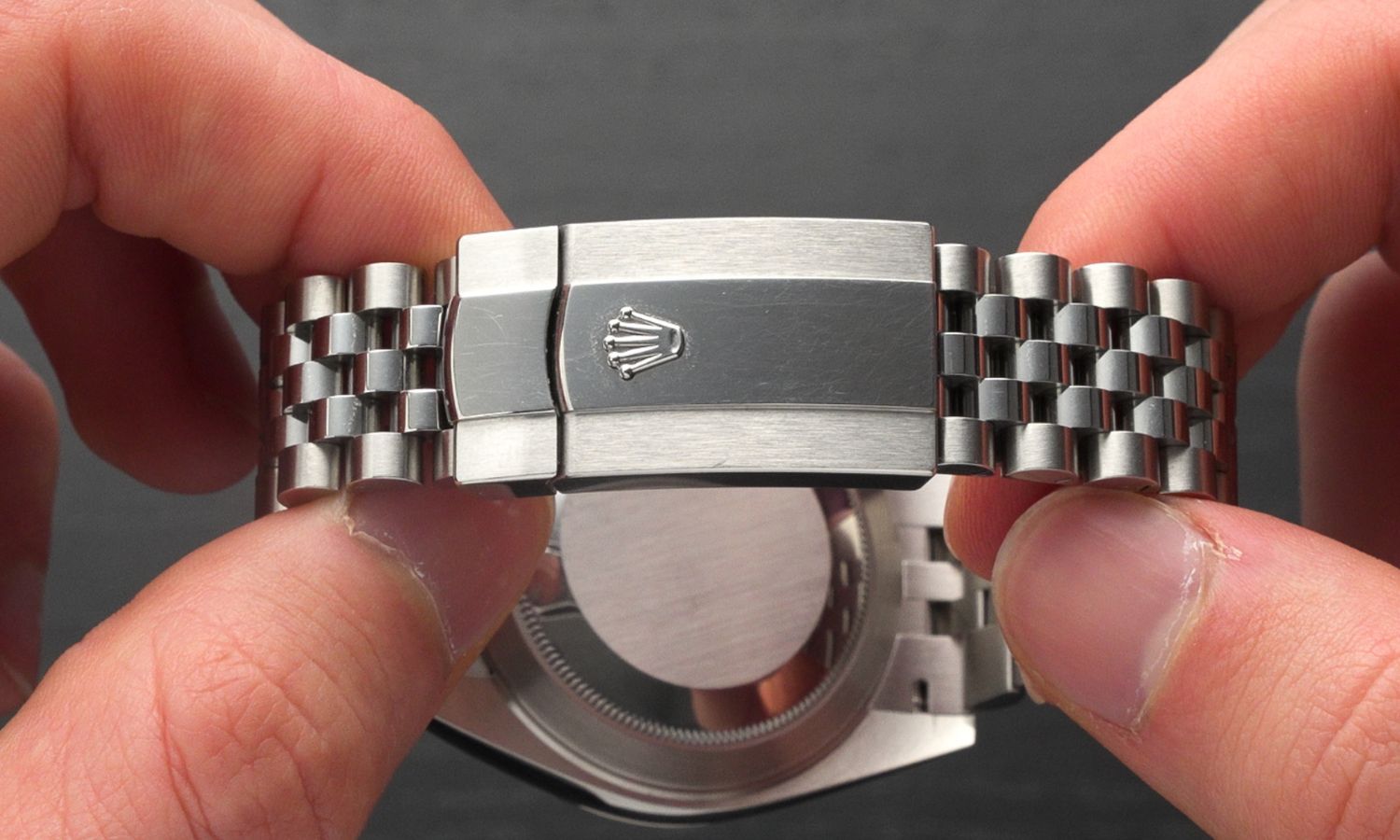 Armband und Schließe des Jubilé Armbands der Rolex Datejust 41 Referenz 126334 in zwei Händen gehalten vor grauem Hintergrund
