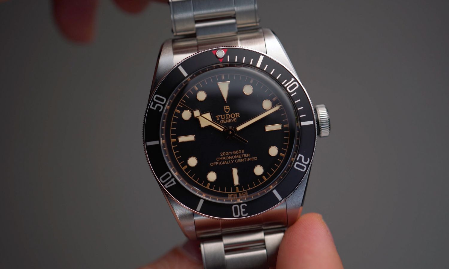 TUDOR Black Bay 58 Referenz M79030N-0001 mit schwarzem Zifferblatt und schwarzer Lünette am Edelstahlarmband in zwei Händen gehalten vor grauem Hintergrund