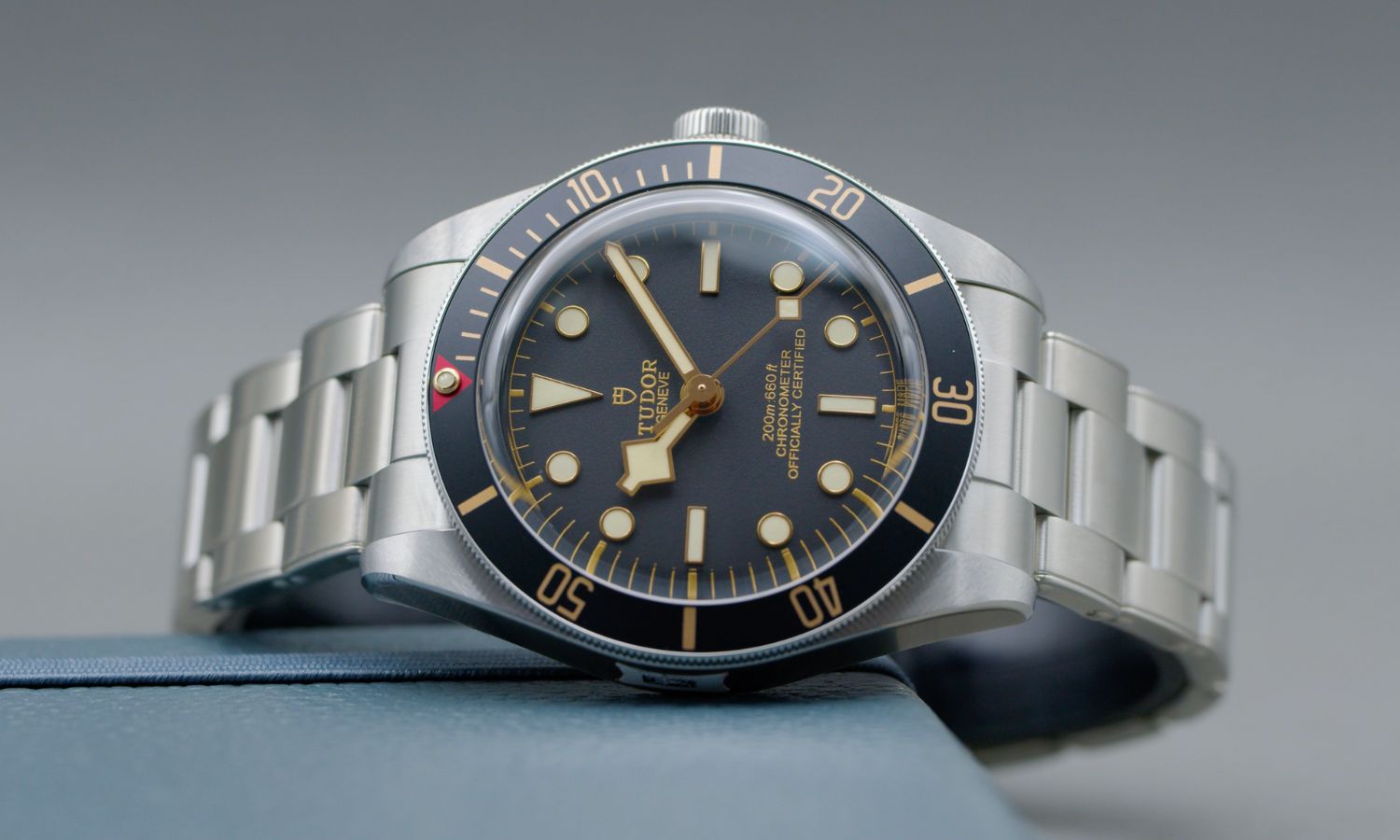 TUDOR Black Bay 58 Referenz M79030N-0001 mit schwarzem Zifferblatt und schwarzer Lünette am Edelstahlarmband liegend vor grauem Hintergrund