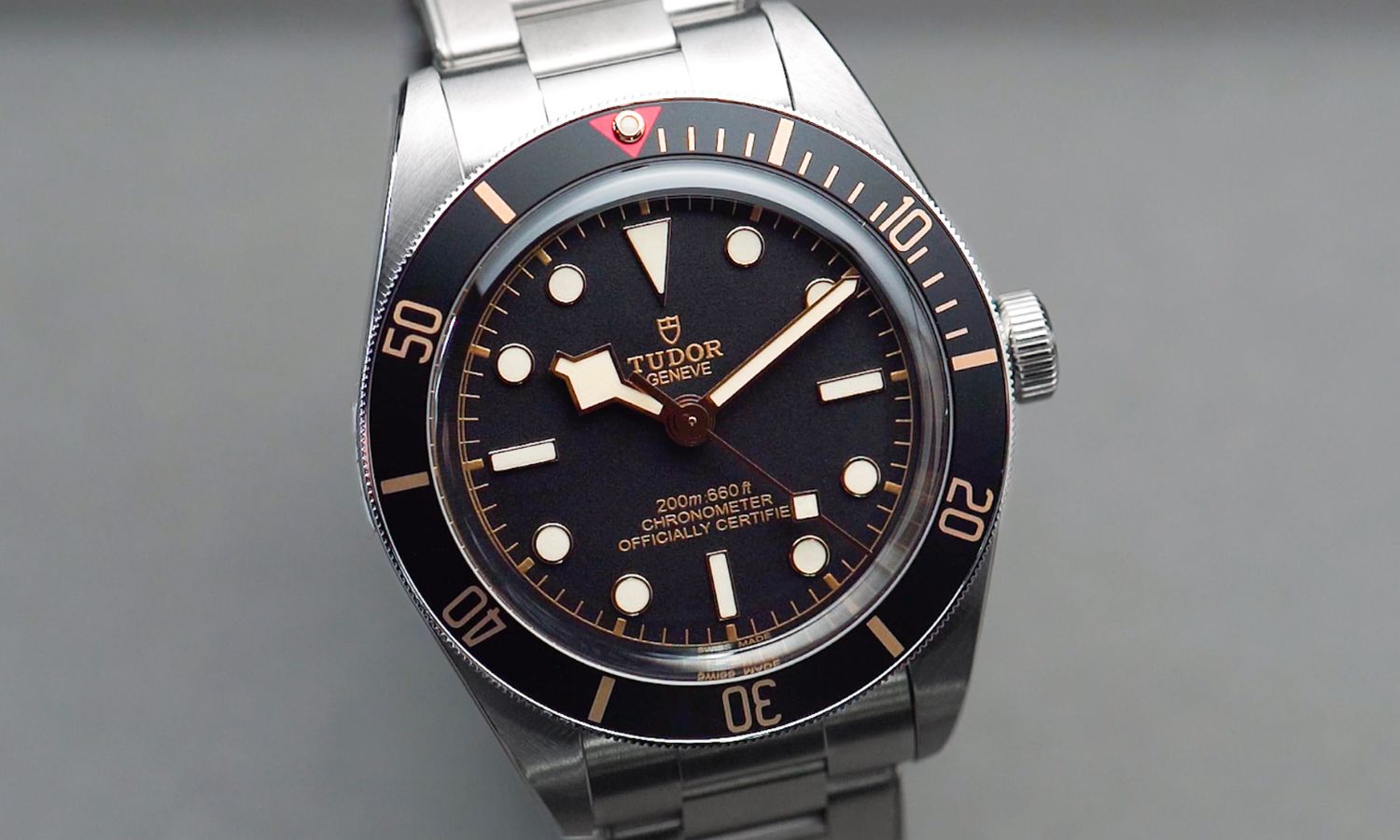 TUDOR Black Bay 58 mit schwarzem Zifferblatt und schwarzer Lünette am Edelstahlarmband abgebildet vor grauem Hintergrund