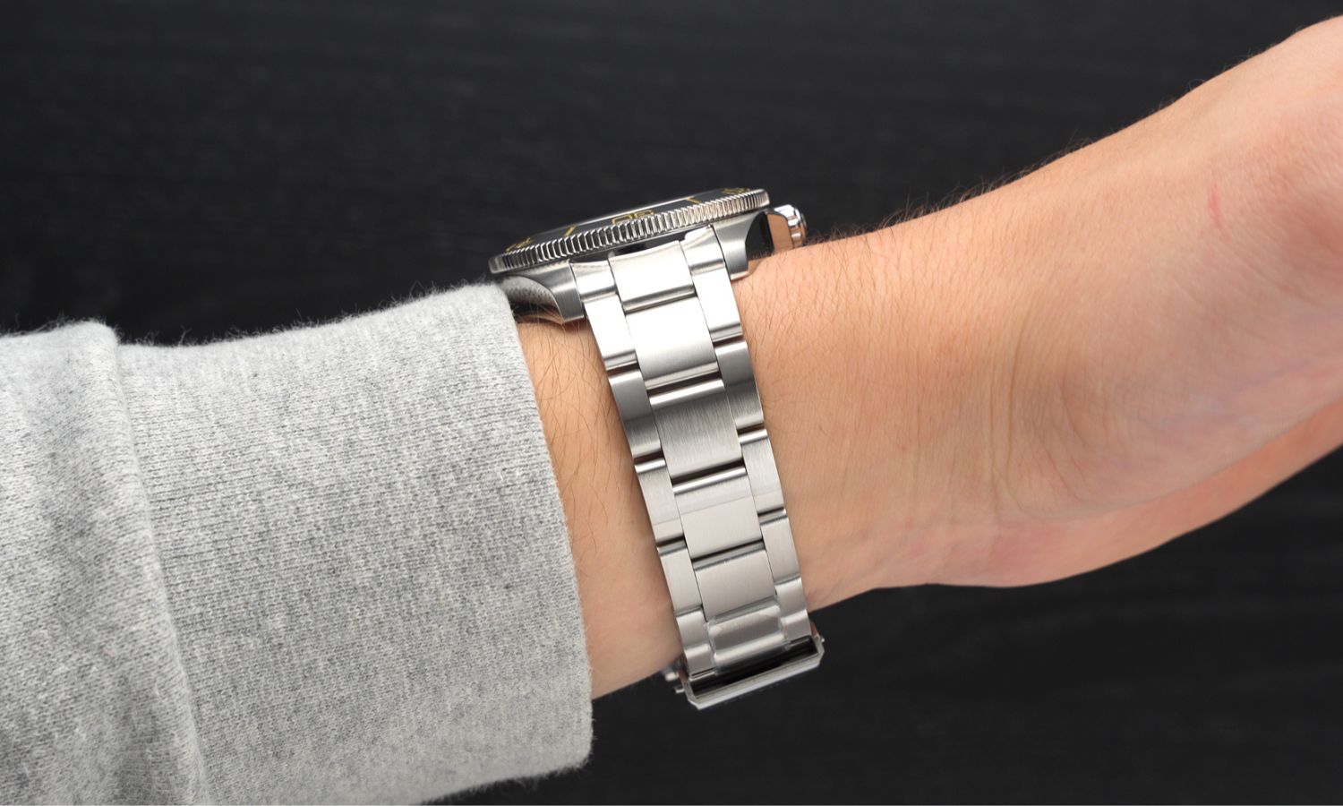Edelstahlarmband der Certina DS Action Diver 40.5mm Powermatic 80 Referenz: C048.407.11.051.01 an einem Handgelenk mit grauem Ärmel getragen vor schwarzem Hintergrund