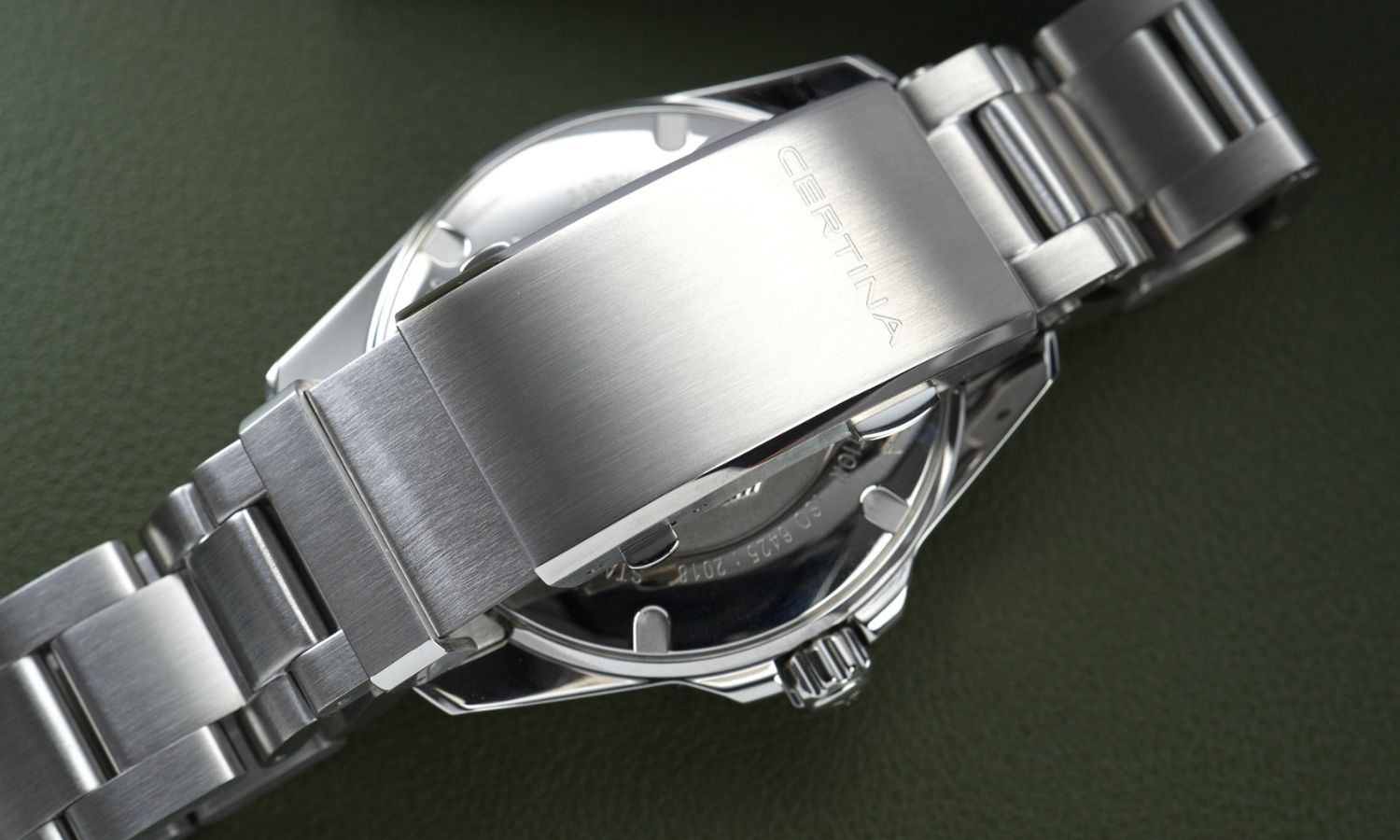 Edelstahlarmband und Schließe der Certina DS Action Diver 40,5mm Powermatic 80 Referenz: C048.407.11.051.01 abgebildet vor dunkelgrünem Hintergrund