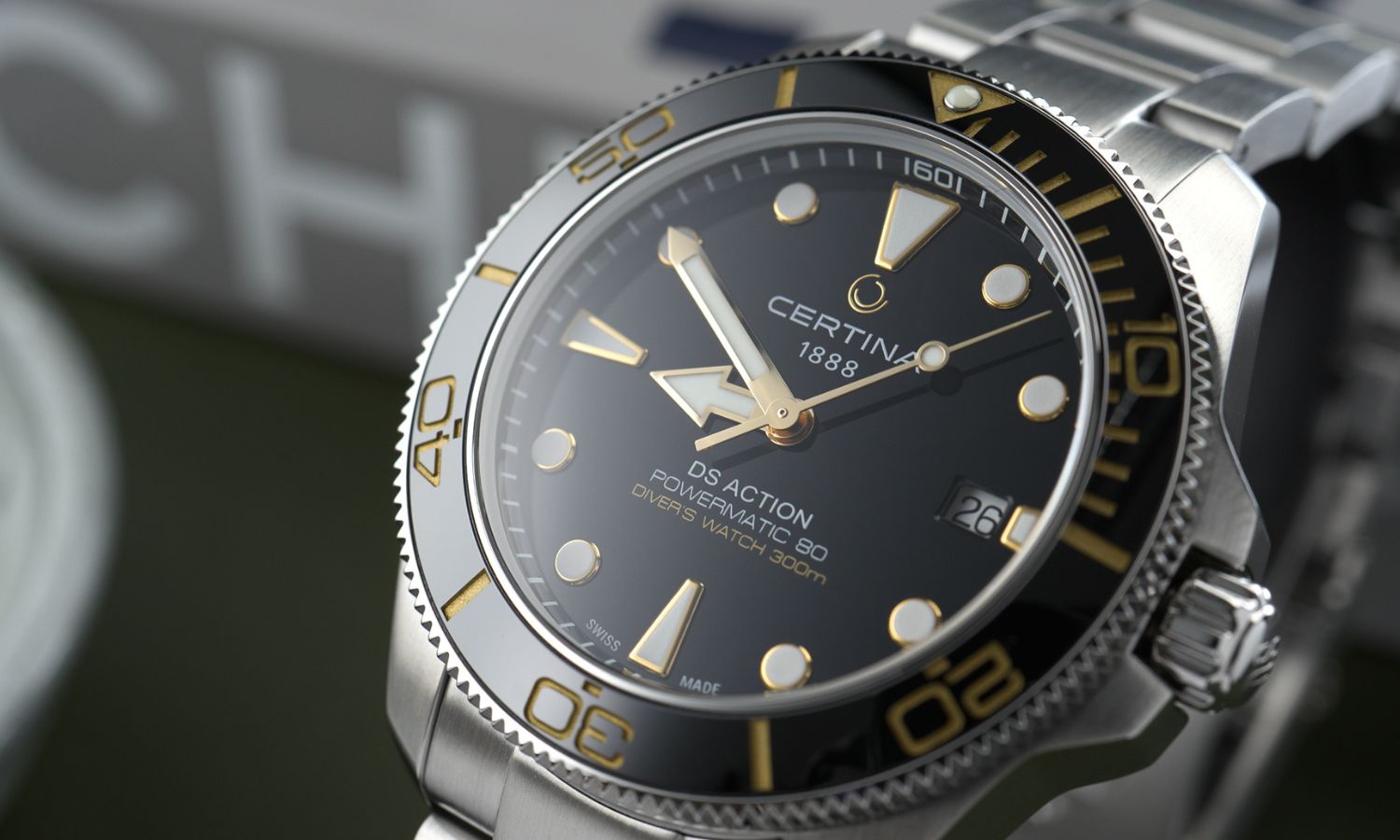Nahaufnahme des schwarzen Zifferblatts der Certina DS Action Diver 40,5mm Powermatic 80 Referenz: C048.407.11.051.01 abgebildet vor dunkelgrünem Hintergrund