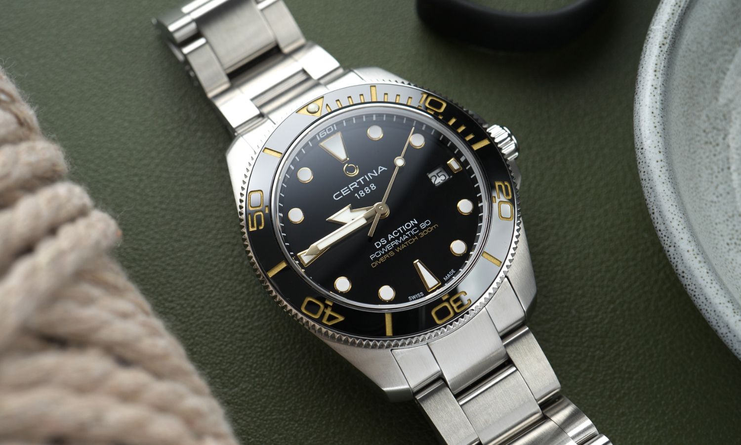 Certina DS Action Diver 40,5mm Powermatic 80 Referenz: C048.407.11.051.01 mit schwarzem Zifferblatt am Edelstahlarmband liegend vor dunkelgrünem Hintergrund