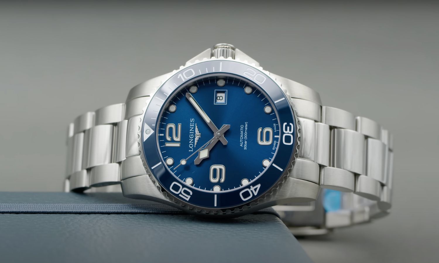 Longines HydroConquest 41 mit blauem Zifferblatt am Edelstahlarmband auf der Seite liegend vor grauem Hintergrund