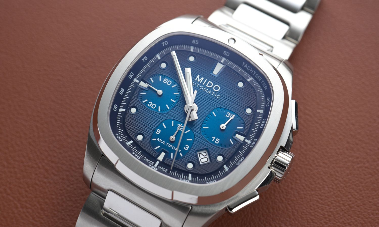 Mido Multifort TV Chronograph Referenz: M049.527.11.041.00 mit blauem Zifferblatt am Edelstahlarmband liegend vor braunem Hintergrund