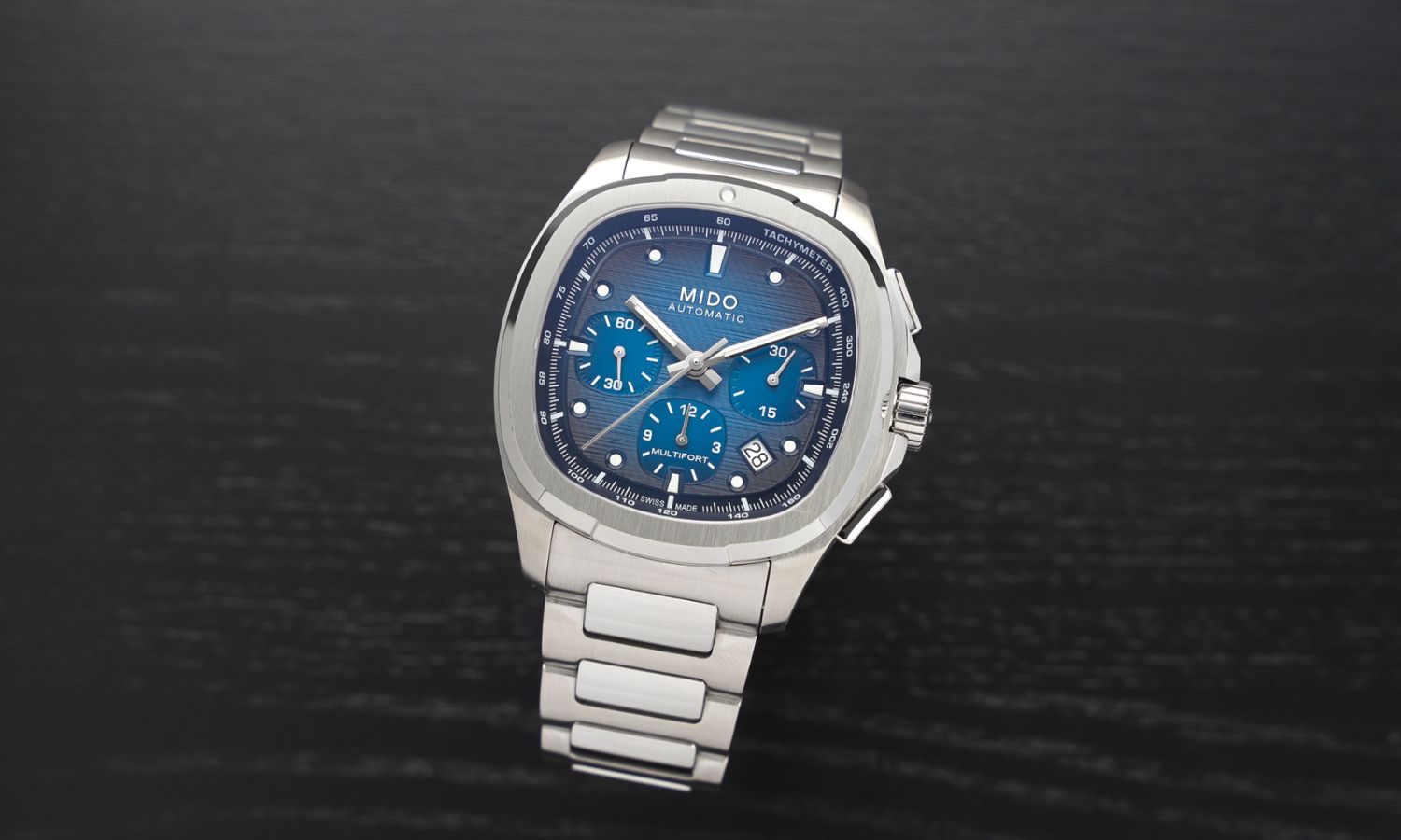 Mido Multifort TV Chronograph Referenz: M049.527.11.041.00 mit blauem Zifferblatt am Edelstahlarmband stehend vor schwarzem Hintergrund