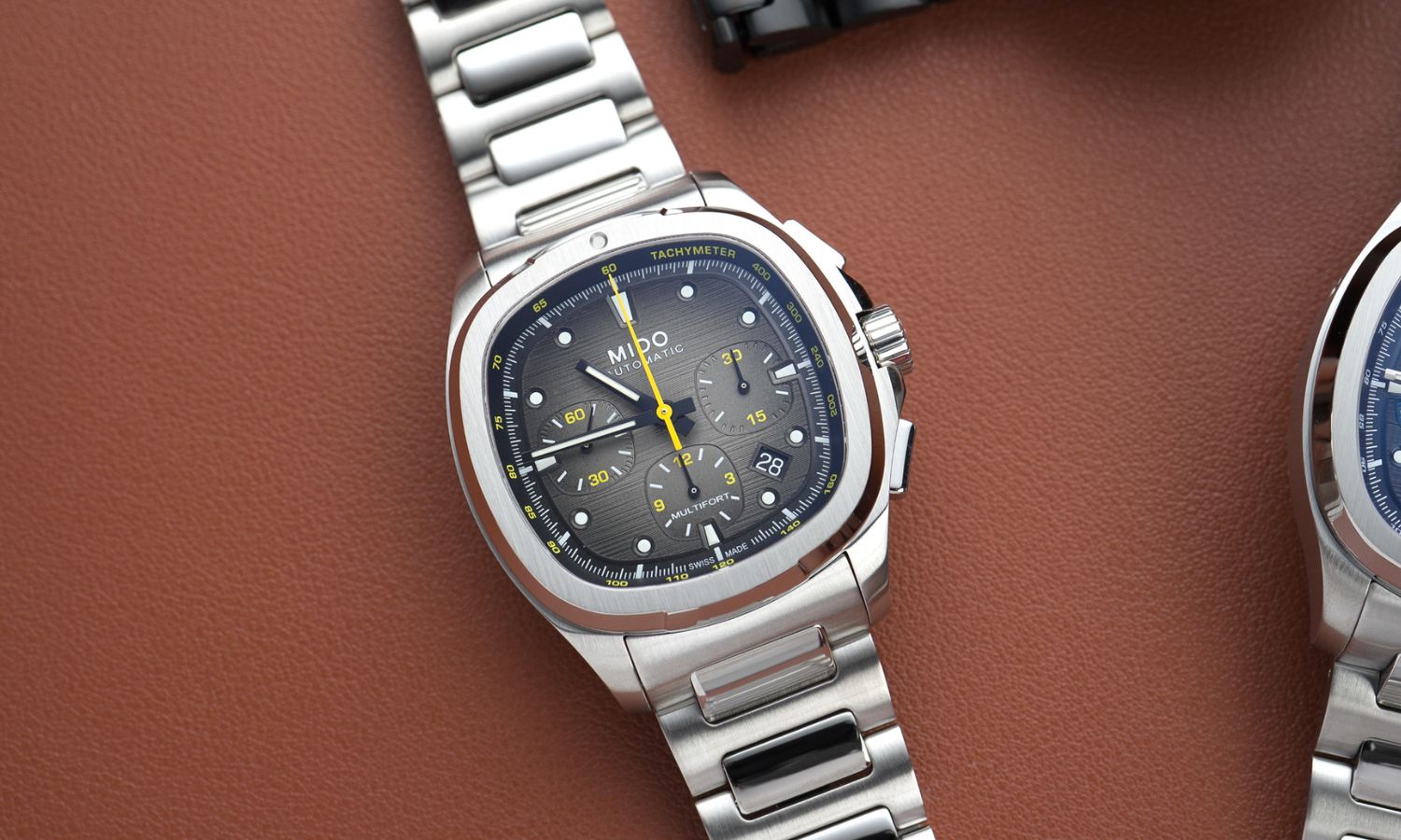 Mido Multifort TV Chronograph Referenz: M049.527.11.081.00 mit grauem Zifferblatt am Edelstahlarmband liegend vor braunem Hintergrund