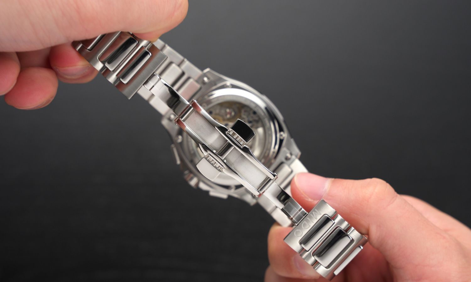 Das Edelstahlarmband und die Schließe des Mido Multifort TV Chronographen in zwei Händen gehalten