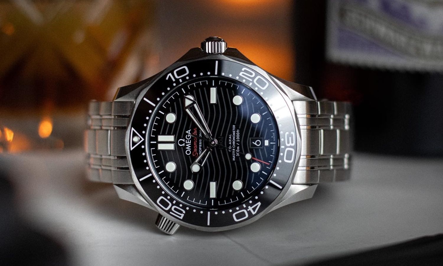 OMEGA Seamaster Diver 300M 42 mit schwarzem Zifferblatt am Edelstahlarmband auf der Seite liegend vor dunklem Hintergrund