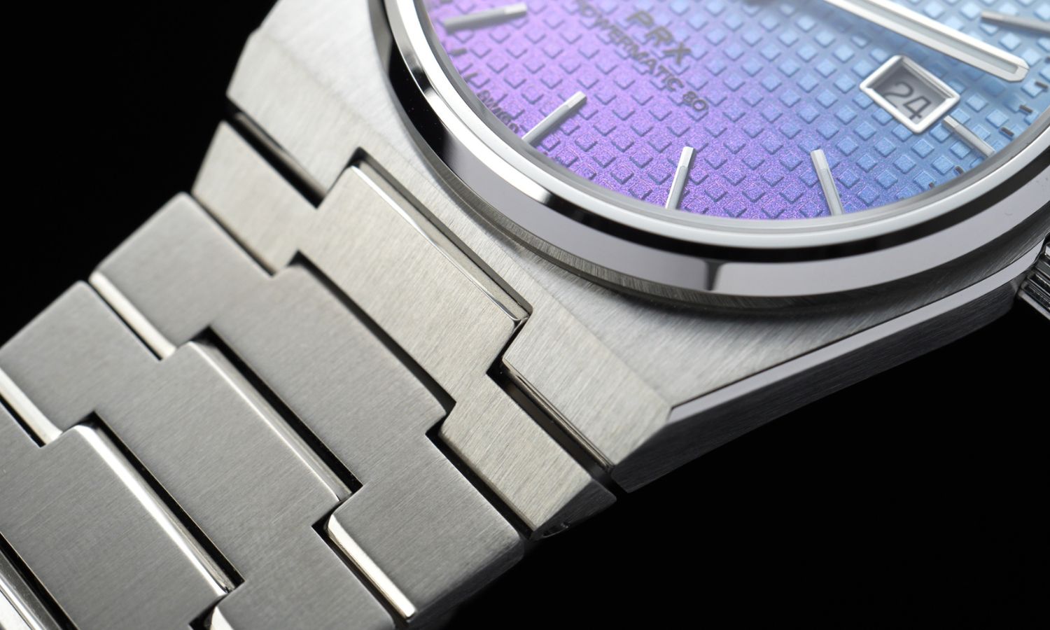 Nahaufnahme des Gehäuses und Edelstahlarmbands der Tissot PRX Powermatic 80 Gradient Referenz T137.407.11.351.01 mit blau-violettem Zifferblatt vor schwarzem Hintergrund