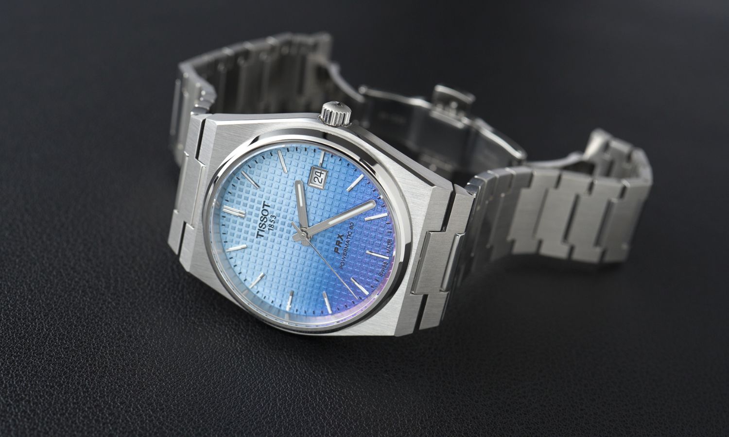 Tissot PRX Powermatic 80 Gradient Referenz T137.407.11.351.01 mit blau-violettem Zifferblatt am Edelstahlarmband seitlich liegend vor schwarzem Hintergrund