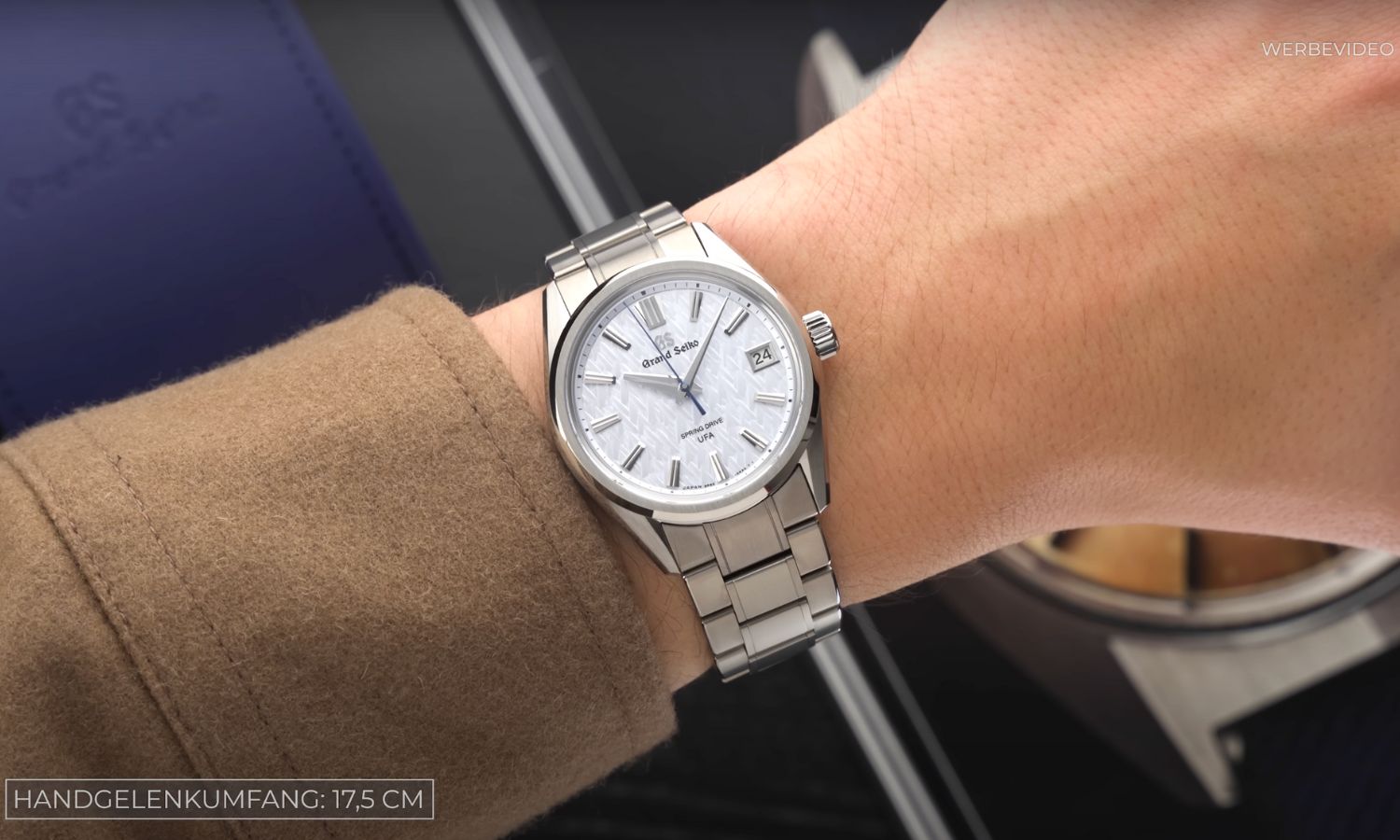 Grand Seiko Evolution 9 SLGB003 Ice Forest mit hellblauem Zifferblatt am Titanarmband an einem Handgelenk mit braunem Ärmel getragen