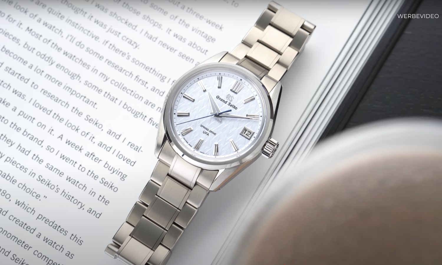 Grand Seiko Evolution 9 SLGB003 Ice Forest mit hellblauem Zifferblatt am Titanarmband auf einem Buch liegend