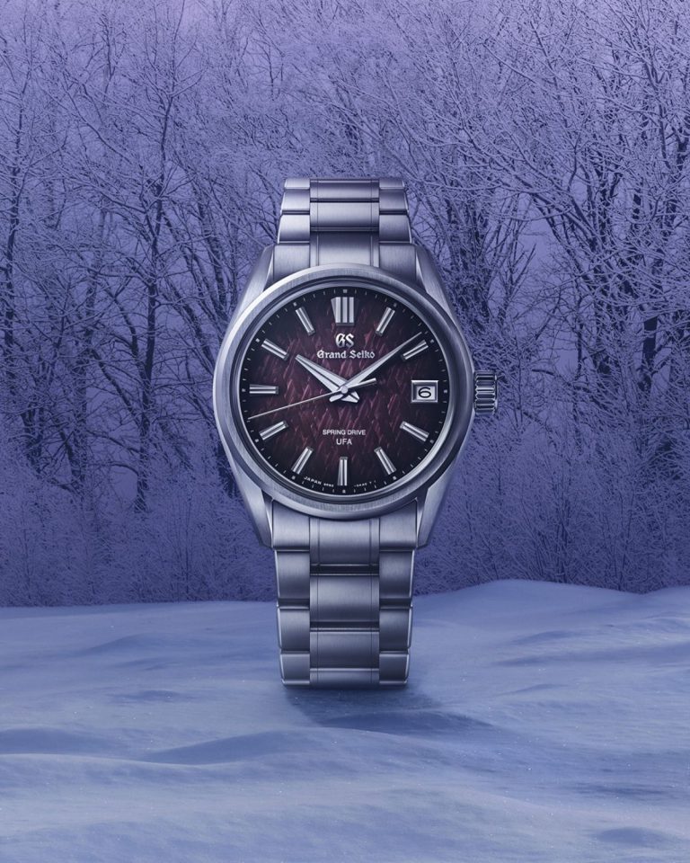 Grand Seiko SLGB005 „Violet Dawn“ mit violettem Zifferblatt am Edelstahlarmband von vorne abgebildet auf Schnee vor einem Wald mit violettem Hintergrund