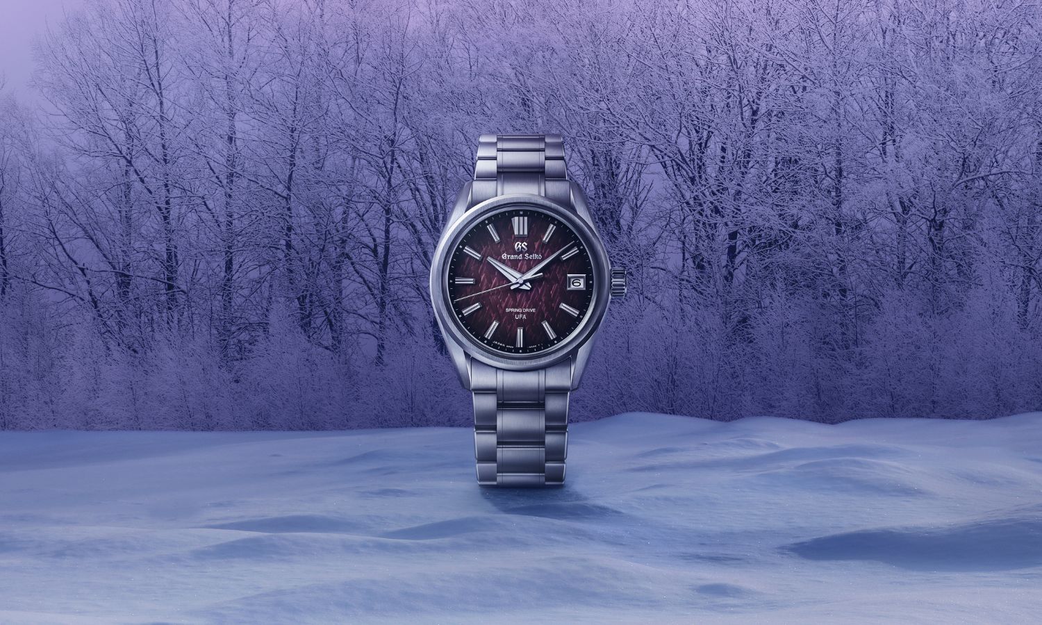 Grand Seiko SLGB005 „Violet Dawn“ mit violettem Zifferblatt am Edelstahlarmband von vorne abgebildet auf Schnee vor einem Wald mit violettem Hintergrund