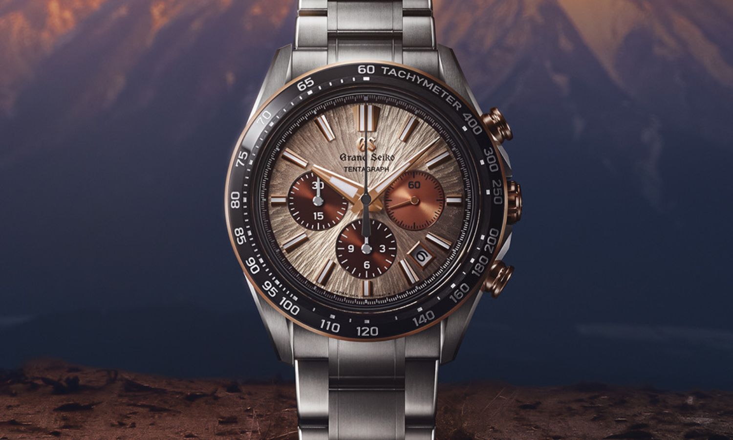 Grand Seiko SLGC006 Sunrise Tentagraph mit kupferfarbenem Zifferblatt am Edelstahlarmband von vorne abgebildet vor einem Berg im Hintergrund